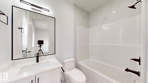 Bathroom featuring a white vanity with an integrated rectangular sink, a large framed mirror, and a contemporary linear light fixture - 1707 18 Street Nw, Edmonton, AB - Indoor Photo Showing Bathroom