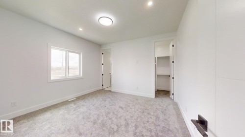 Spacious room featuring neutral carpeting, a dual-pane window with white trim, and a white ceiling with recessed lighting and a flush mount fixture - 1707 18 Street Nw, Edmonton, AB - Indoor Photo Showing Other Room
