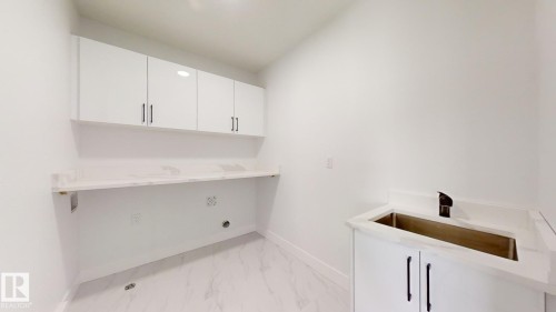 Laundry area featuring white cabinetry, a utility sink with a black faucet, and a spacious countertop - 1707 18 Street Nw, Edmonton, AB - Indoor
