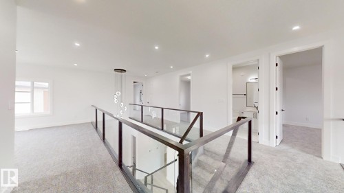 Second-story landing featuring light gray carpet, recessed lighting, and a contemporary linear chandelier - 1707 18 Street Nw, Edmonton, AB - Indoor Photo Showing Other Room