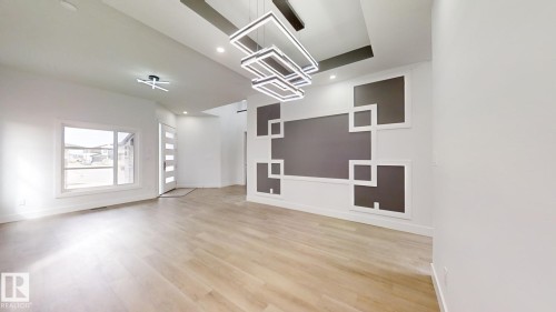 Open-concept living space featuring wood-finish flooring, a contemporary decorative accent wall with geometric molding, and a modern multi-tiered chandelier - 1707 18 Street Nw, Edmonton, AB - Indoor Photo Showing Other Room