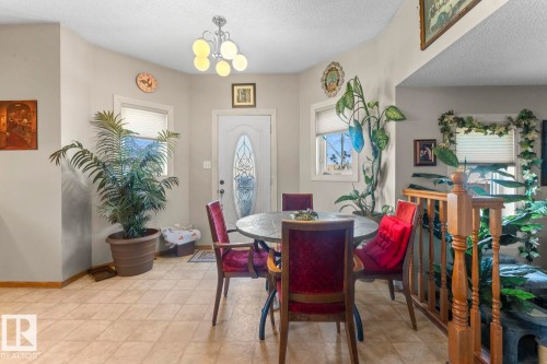 Front entry area featuring a decorative glass paneled door, two windows with horizontal blinds, and a five-light chandelier - 1414 7 Avenue, Cold Lake, AB - Indoor Photo Showing Dining Room