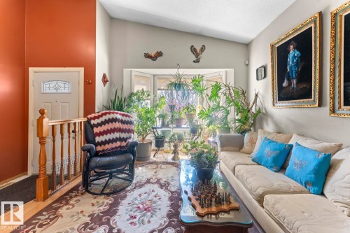 Living area featuring a prominent bay window, a vaulted ceiling, wood-finish flooring, and a white entry door with decorative glass inserts - 1414 7 Avenue, Cold Lake, AB - Indoor Photo Showing Other Room
