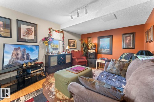 Living area featuring wood-finish flooring, track lighting, and a textured ceiling - 1414 7 Avenue, Cold Lake, AB - Indoor