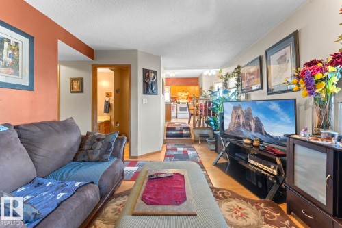 Open concept living area featuring wood-finish flooring, a neutral wall color, and a partial view of the kitchen with wood cabinetry - 1414 7 Avenue, Cold Lake, AB - Indoor Photo Showing Living Room