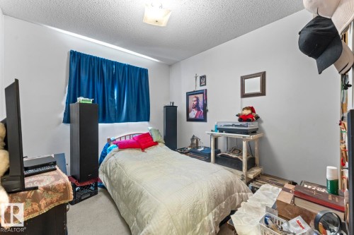 Bedroom featuring a single window with blue curtains, wall-to-wall carpeting, and a ceiling-mounted light fixture - 1414 7 Avenue, Cold Lake, AB - Indoor Photo Showing Bedroom