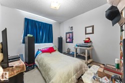 Bedroom featuring a single window with blue curtains, wall-to-wall carpeting, and a ceiling-mounted light fixture - 