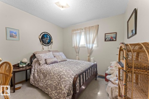 Bedroom featuring a window with privacy blinds, neutral wall paint, textured ceiling, and an overhead light fixture - 1414 7 Avenue, Cold Lake, AB - Indoor Photo Showing Bedroom