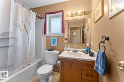 Full bathroom featuring a white tub/shower combination, a toilet, and a vanity with a white countertop and wood-finish cabinetry - 