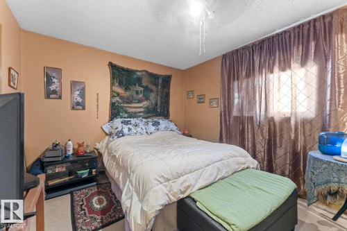 Bedroom featuring neutral walls, a textured ceiling, a window with sheer curtains, and light-colored flooring - 1414 7 Avenue, Cold Lake, AB - Indoor Photo Showing Bedroom