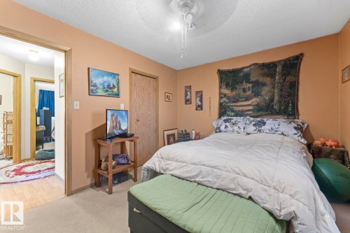 Carpeted bedroom featuring a ceiling fan with light fixture, natural wood-finish door, and warm-toned wall paint - 1414 7 Avenue, Cold Lake, AB - Indoor Photo Showing Bedroom