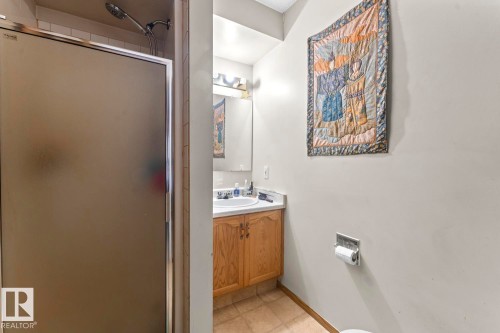 Bathroom featuring a shower with frosted glass doors, a vanity with wood-finish cabinetry, a white basin sink, and a mirrored medicine cabinet - 1414 7 Avenue, Cold Lake, AB - Indoor Photo Showing Bathroom