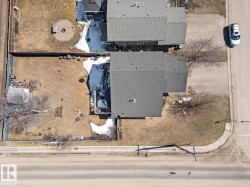 Property featuring a gray shingled roof, a fenced backyard, and a paved street frontage with sidewalk - 