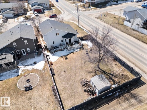 Rear exterior featuring a second-story deck, a fenced yard, a circular patio with a fire pit, and a detached storage shed - 1414 7 Avenue, Cold Lake, AB - Outdoor