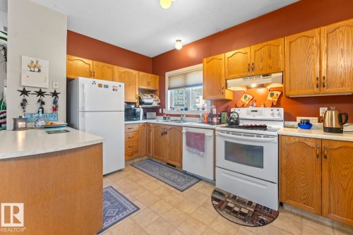 Kitchen featuring wood-finish cabinetry, white appliances, and light-colored countertops - 1414 7 Avenue, Cold Lake, AB - Indoor Photo Showing Kitchen