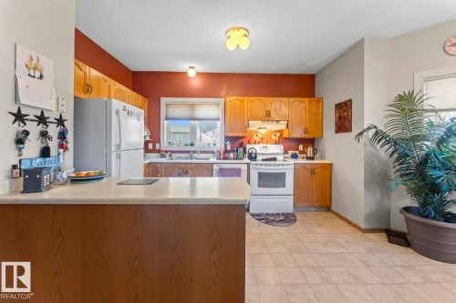 Kitchen featuring wood-finish cabinetry, solid surface countertops, and an integrated counter-height breakfast bar - 1414 7 Avenue, Cold Lake, AB - Indoor Photo Showing Kitchen