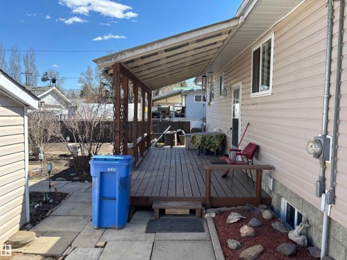 Covered wood-finish deck with a wood railing and support beams - 4824 49 Avenue, Sangudo, AB - Outdoor With Exterior