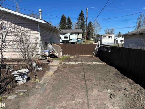 Rear yard featuring a brown privacy fence, a cleared earth surface, and a concrete paver path - 4824 49 Avenue, Sangudo, AB - Outdoor