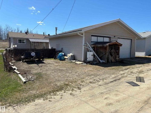 Detached garage with two white overhead doors and beige vinyl siding - 4824 49 Avenue, Sangudo, AB - Outdoor With Exterior