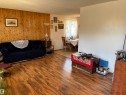 Spacious room featuring wood-finish flooring, a full-height wood panel accent wall, and painted walls - 4824 49 Avenue, Sangudo, AB  - Indoor Photo Showing Living Room 