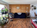 Interior living area featuring wood-finish flooring, a prominent wood accent wall, and textured ceiling - 4824 49 Avenue, Sangudo, AB  - Indoor Photo Showing Living Room 