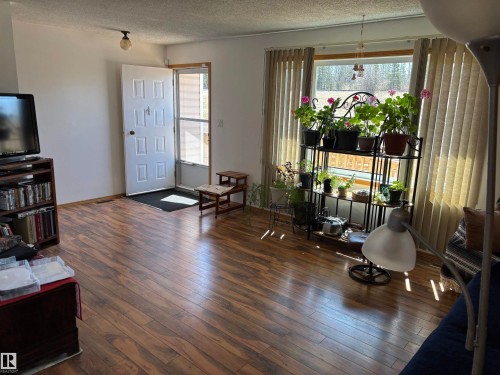 Expansive room featuring wood-finish flooring, white walls, and a large window with vertical blinds - 4824 49 Avenue, Sangudo, AB - Indoor Photo Showing Living Room
