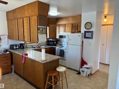 Kitchen featuring wood-finish cabinetry, light-toned countertops, and a white tile backsplash - 4824 49 Avenue, Sangudo, AB - Indoor Photo Showing Kitchen