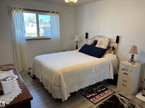 Bedroom featuring wood-finish flooring, a window with sheer curtains, and a ceiling fan with integrated lighting - 4824 49 Avenue, Sangudo, AB - Indoor Photo Showing Bedroom