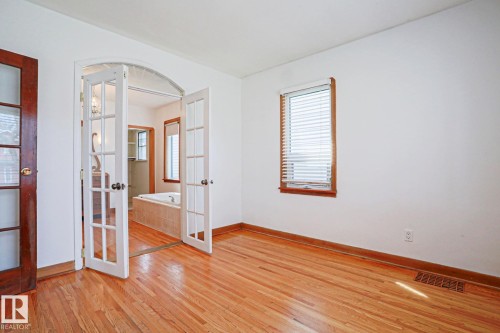 Room featuring wood-finish flooring, white walls, and a window with wood trim - 9611 81 Avenue, Edmonton, AB - Indoor Photo Showing Other Room