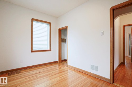 Hardwood flooring throughout, featuring a window with integrated blinds, and natural wood trim - 9611 81 Avenue, Edmonton, AB - Indoor Photo Showing Other Room