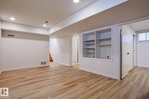 Spacious room featuring wood-finish flooring, recessed lighting, white walls, built-in shelving, and a visible window with blinds - 9611 81 Avenue, Edmonton, AB - Indoor Photo Showing Other Room