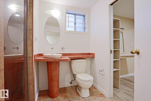 Bathroom featuring a vessel sink on a pedestal base, a wall-mounted oval mirror, and an adjacent toilet - 9611 81 Avenue, Edmonton, AB - Indoor Photo Showing Bathroom