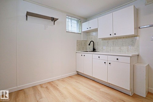Utility area featuring light wood-finish flooring, white panel walls, and a window with blinds - 9611 81 Avenue, Edmonton, AB - Indoor