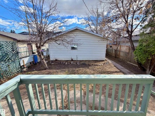 Expansive backyard featuring a detached garage with vinyl siding, natural wood fencing, a concrete paver pathway, and mature trees - 9611 81 Avenue, Edmonton, AB - Outdoor