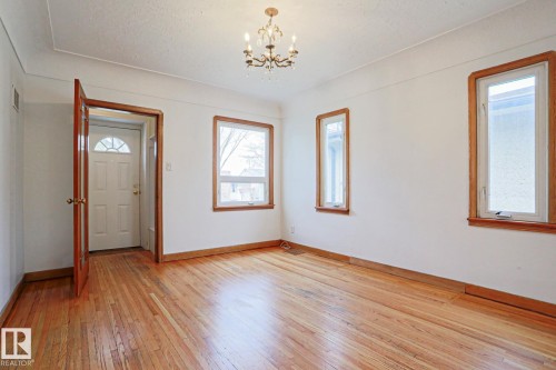 Spacious room featuring wood-finish flooring, white walls, and warm wood trim - 9611 81 Avenue, Edmonton, AB - Indoor Photo Showing Other Room