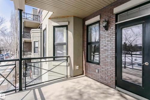 The property features a private balcony with a concrete floor and a black metal and glass railing - 211 10808 71 Avenue, Edmonton, AB - Outdoor With Exterior