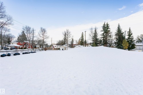 The property features a large, snow-covered yard with mature evergreen trees visible in the distance - 211 10808 71 Avenue, Edmonton, AB - Outdoor With View