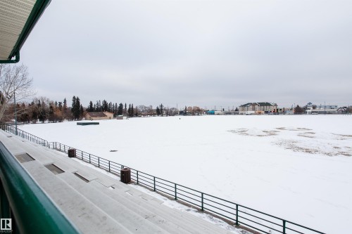 This property offers views of a snow-covered field, bordered by trees and distant buildings - 211 10808 71 Avenue, Edmonton, AB - Outdoor With View