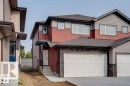 Multi-level residence featuring red and grey siding, a front entry with black railing, an attached garage with panel door, dark shingles, and multiple windows with white trim - 39 Caledon Crescent, Spruce Grove, AB  - Outdoor 