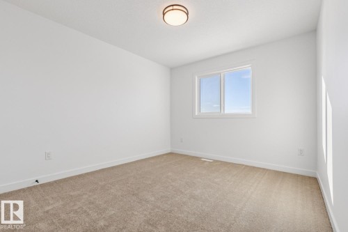 Neutral tone wall paint, light brown carpet flooring, white trim, and a contemporary ceiling light fixture - 39 Caledon Crescent, Spruce Grove, AB - Indoor Photo Showing Other Room