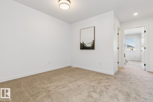 Neutral-toned carpeting extends throughout this interior space, complemented by crisp white walls and baseboards - 39 Caledon Crescent, Spruce Grove, AB - Indoor Photo Showing Other Room