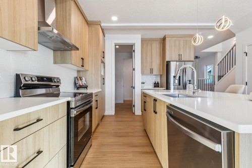 Modern kitchen featuring wood-finish cabinetry, stainless steel appliances, and light-toned countertops - 39 Caledon Crescent, Spruce Grove, AB - Indoor Photo Showing Kitchen With Upgraded Kitchen