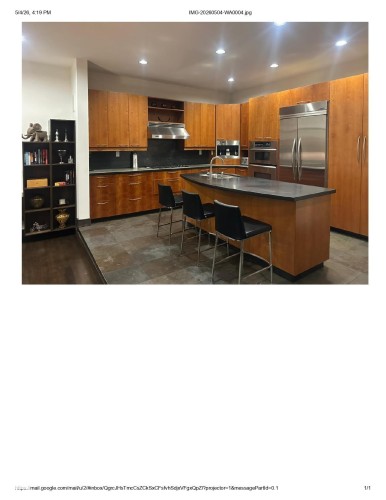 Modern kitchen featuring extensive wood cabinetry, an oversized island with seating, stainless steel appliances, and dark countertops - 9012 98 Street, Edmonton, AB - Other