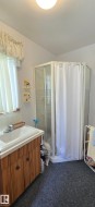 Compact bathroom featuring a corner shower enclosure with clear glass panels and a shower curtain - 