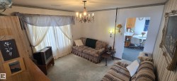 Living area with light-colored carpet flooring and a central chandelier - 