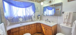 Corner vanity featuring a light-toned countertop and built-in wood-finish cabinetry - 