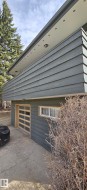 Contemporary exterior with dark siding and a prominent overhang featuring recessed lighting - 