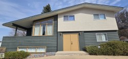 Split-level residence featuring a prominent balcony, angled roofline, and dual-tone exterior with stucco and horizontal siding - 