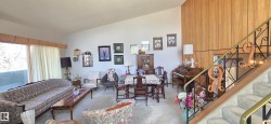 Vaulted ceilings enhance the main living area, featuring a full-wall picture window and light wood-paneled accent wall - 