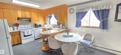 Kitchen featuring wood cabinetry, white appliances, a curved breakfast bar, and a patterned backsplash - 